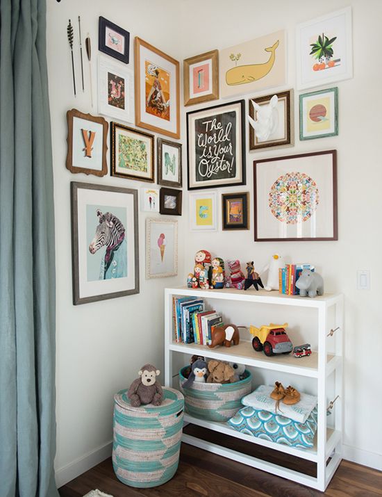 a lovely corner gallery wall in a kids' room with pretty monograms, posters and faux taxidermy plus arrows on top is wow