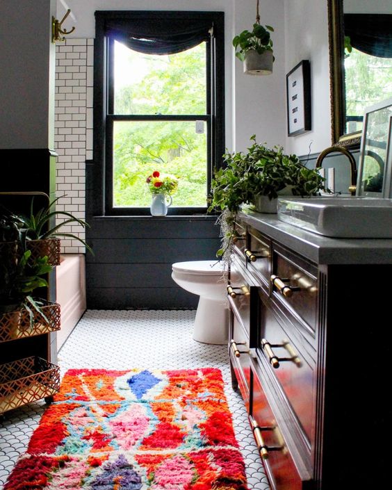 a lovely eclectic bathroom with subway and fishscale tiles, a bold rug, potted plants and touches of black and green