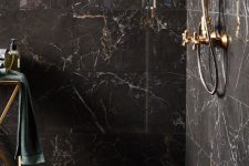 a lovely glam black and gold bathroom with marble tiles, gold fixtures and a gold stand, dark towels is wow