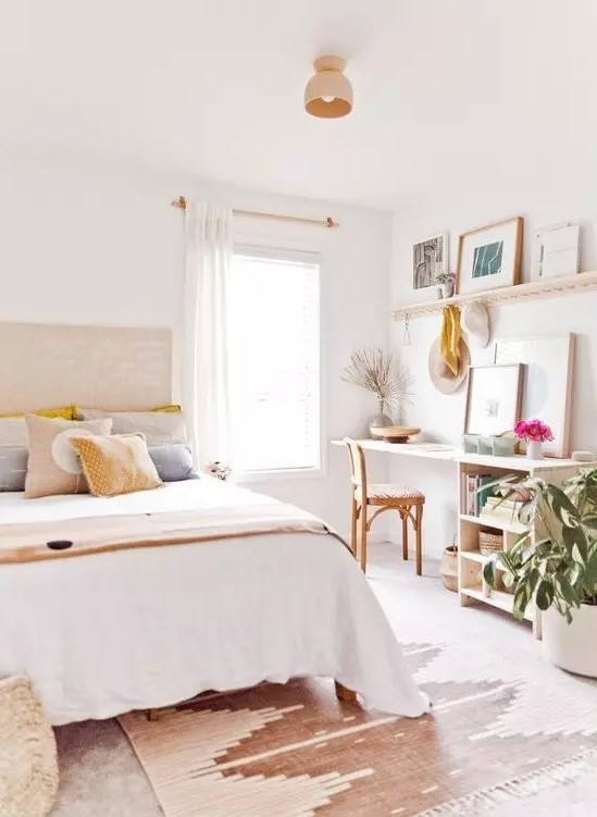 a lovely light filled teen bedroom with a bed, a small desk with storage, a ledge with artworks and potted plants