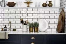 a lovely mid-century modern kitchen with black cabinets, white stone countertops, a white subway tile backsplash and black grout