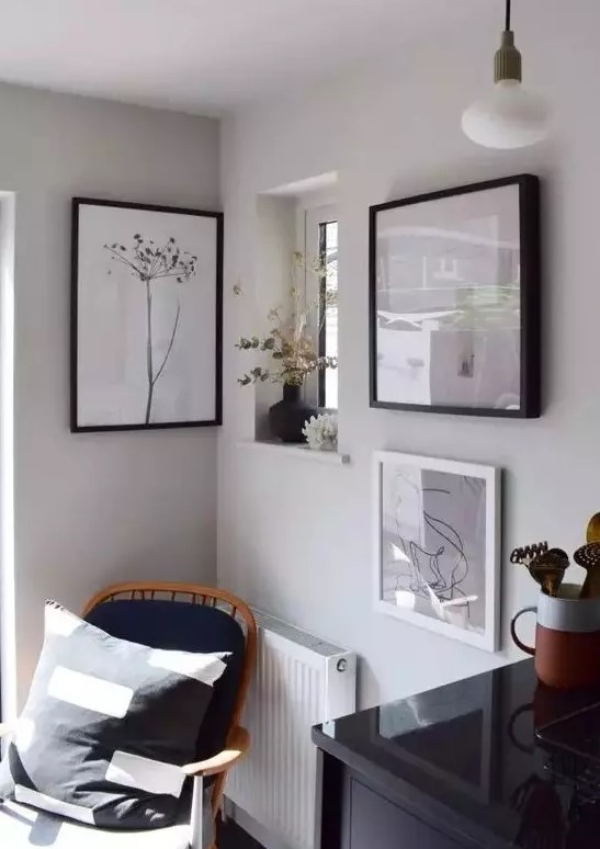 a lovely nook with a black chair with a pillow, a mini gallery wall and some dried blooms and plants