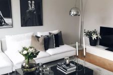 a luxurious black and white living roo with stylish contemporary furniture, black and mirro coffee tables and a dark gallery wall