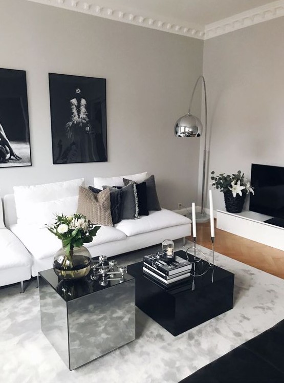 a luxurious black and white living roo with stylish contemporary furniture, black and mirro coffee tables and a dark gallery wall