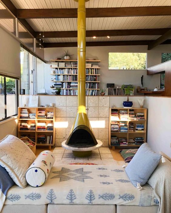 a mid-century modern living room with a yellow Malm fireplace, a daybed and some bookshelves is a lovely space