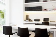 a minimalist black and white home office with open shelves, a desk and a meeting table with black chairs