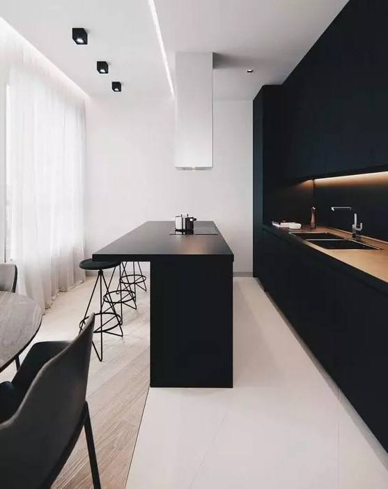 a minimalist black kitchen with built-in lights, a matte kitchen island and a white hood is a stylish and chic idea to rock