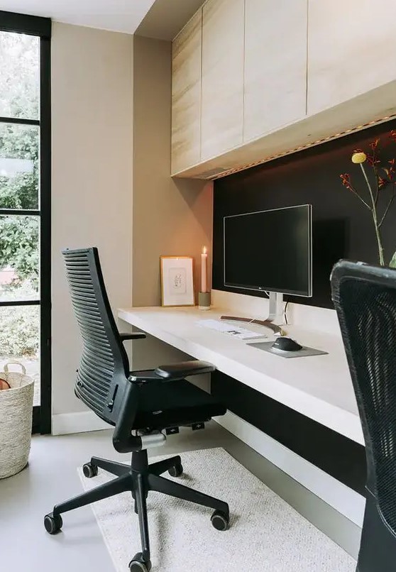 a minimalist home office with a light-stained storage cabinet, a floating desk, a black chair and a black accent wall is a welcoming space