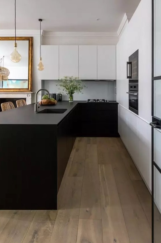 a minimalist kitchen with matte white and black cabinets, a large kitchen island, black built-in appliances and pendant lamps