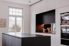 a minimalist kitchen with white cabinets and a black kitchen island, a black additional cabinet and a mirror backsplash, white lamps