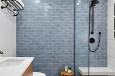 a modern bathroom with a blue tile accent wall, a light-stained vanity, a doorless shower with a wall-mounted bench