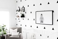 a modern black and white nursery with a patterned wall, a printed rug, a white crib and a penguin artwork