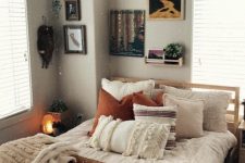 a modern boho teen bedroom with a wooden bed, a rust and white bedding set, a gallery wall and potted plants