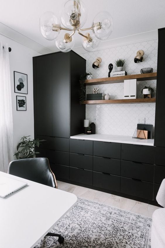 a modern farmhouse home office with black kitchen cabinets and thick shelves, brass and gold touches, a white desk and a black chair
