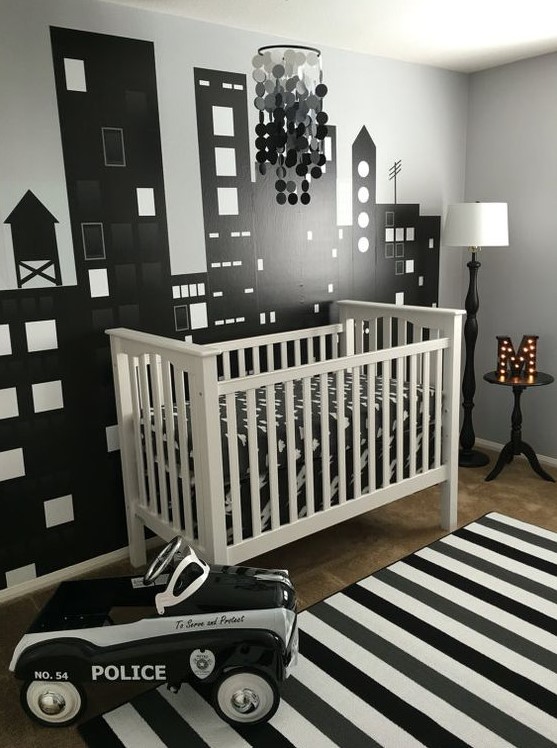 a modern monochromatic nursery with a white crib, a striped rug, an ombre sequin chandelier and a marquee monogram