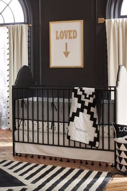 a monochromatic nursery with black walls, arched windows, a black crib and black and white bedding, neutral curtains