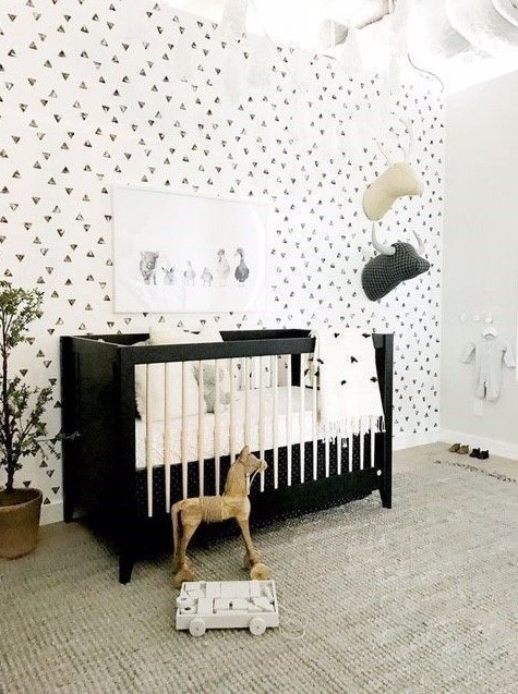 a monochromatic space with a printed wall, a black crib, toy heads on the wall and a large rug