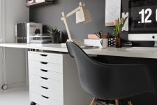 a moody Scandi home office with a black statement wall, chair and some decor and white as the base