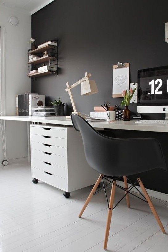 a moody Scandi home office with a black statement wall, chair and some decor and white as the base