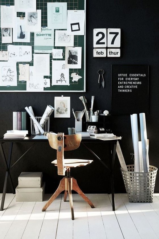 a moody black home office with white floors, a green noteboard with nots, black and white signs and a desk