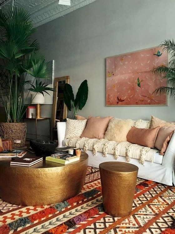 a moody eclectic space with a statement artwork, a boho printed rug, lots of earthy pillows and metal hammered items