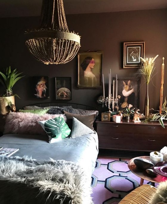 a moody eclectic space with dark walls, a vintage inspired gallery wall, bold bedding and accessories