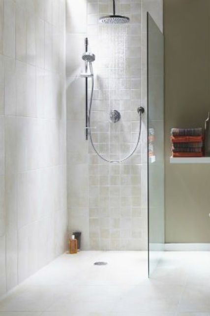 a neutral bathroom with a doorless shower with a skylight and a wall-mounted shelf with towels is a lovely space