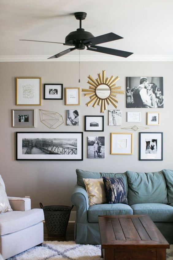 a neutral farmhouse living room with tan walls, a green sofa and a neutral chair, a dark-stained crate table and a catchy gallery wall with black and gold frames