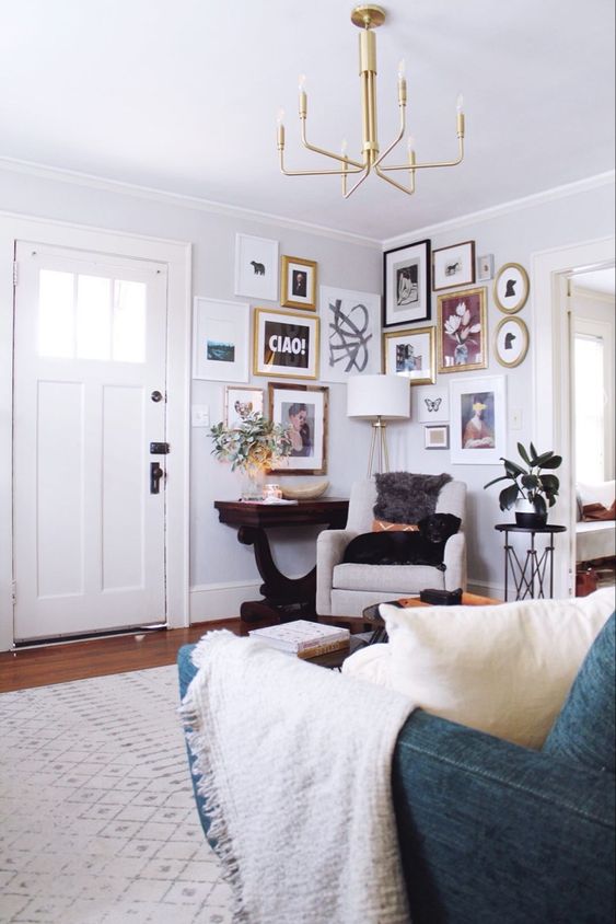 a neutral space with neutral furniture, a dark console table and a corner gallery wall plus a gold chandelier