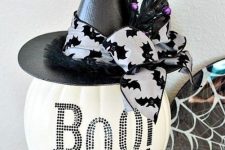a plastic white pumpkin decorated with black sequins and a black witch hat with berries and ribbon for Halloween decor