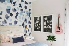 a pretty teen bedroom with a brushstroke accent wall, pink and blue textiles and a pink guitar on the wall