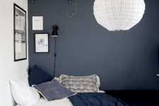 a pretty teen bedroom with a grey accent wall, a bed with black and white bedding, an open shelf, a pendant lamp and a corner gallery wall