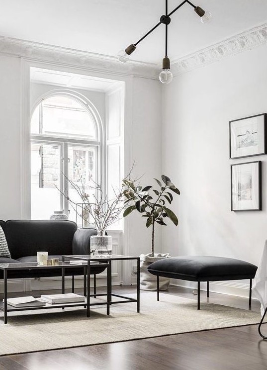 a refined Parisian-inspired living room with chic black furniture, a black chandelier and a gallery wall