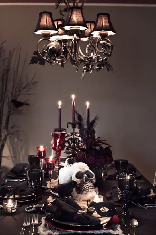 a refined deep burgundy and black Halloween tablescape with purple candles, burgundy candleholders, skulls, crows and black linens is great for a party