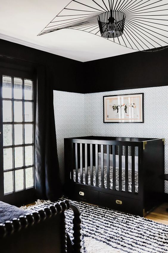 a refined monochromatic nursery with black walls, an accent with black and white bedding, black curtains and a printed rug