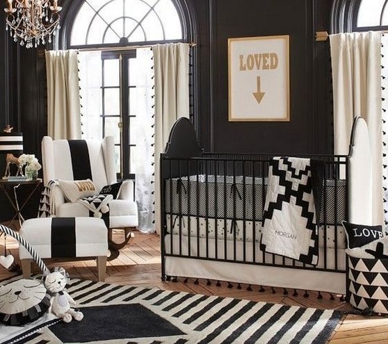 a refined nursery with lots of prints, a crystal chandelier, a black and white crib and gorgeous furniture