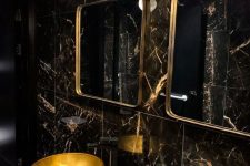 a refined powder room with black marble tiles, gold sinks, gold frame mirrors and catchy pendant lamps