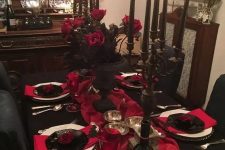 a refined red and black Halloween tablescape with black candelabras and black candles, red roses and red linens