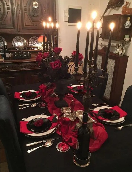a refined red and black Halloween tablescape with black candelabras and black candles, red roses and red linens