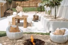a relaxed white tropical outdoor space with a simple metal fire bowl and white chairs around it plus a dining space