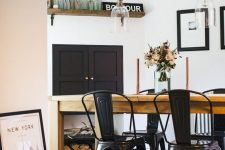 a rustic industrial dining nook with a stained table, black metal chairs, glass pendant lamps and a firewood storage piece