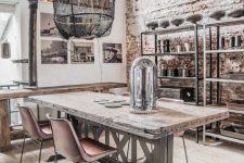 a shabby chic industrial dining space with a brick accent wall, metal shelving units, a rustic dining table and leather chairs, a black pendant lamp