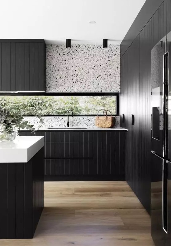 a sleek modern kitchen with black planked cabinets, a white terrazzo backsplash, white countertops and black fixtures is a lovely idea