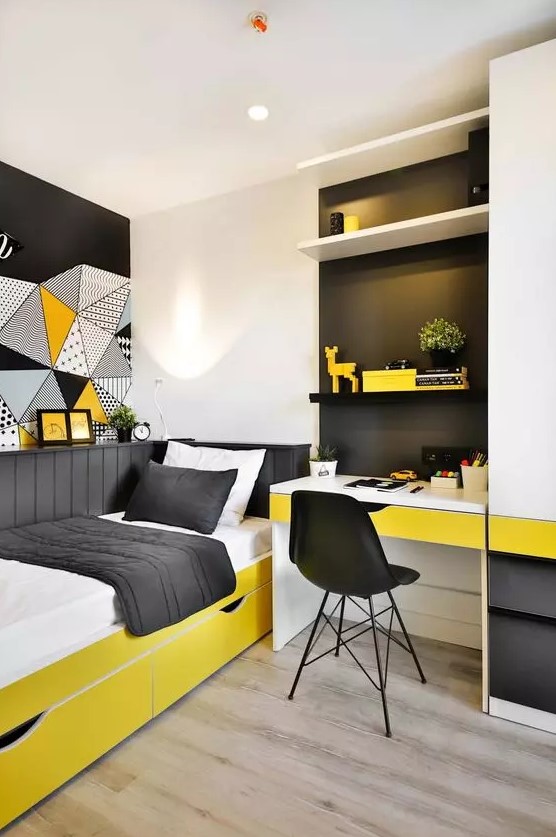 a small and bright teen room with a built in desk and shelves, a bold yellow bed with black and white bedding and bold art on the wall