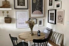 a small and cool dining space with a floating bench, a stained table, black chairs and a catchy corner gallery wall plus a pendant lamp