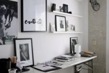 a small black and white home office with a shabby chic desk, a black chair, artworks and shelves