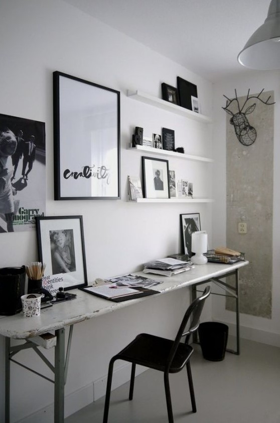 a small black and white home office with a shabby chic desk, a black chair, artworks and shelves