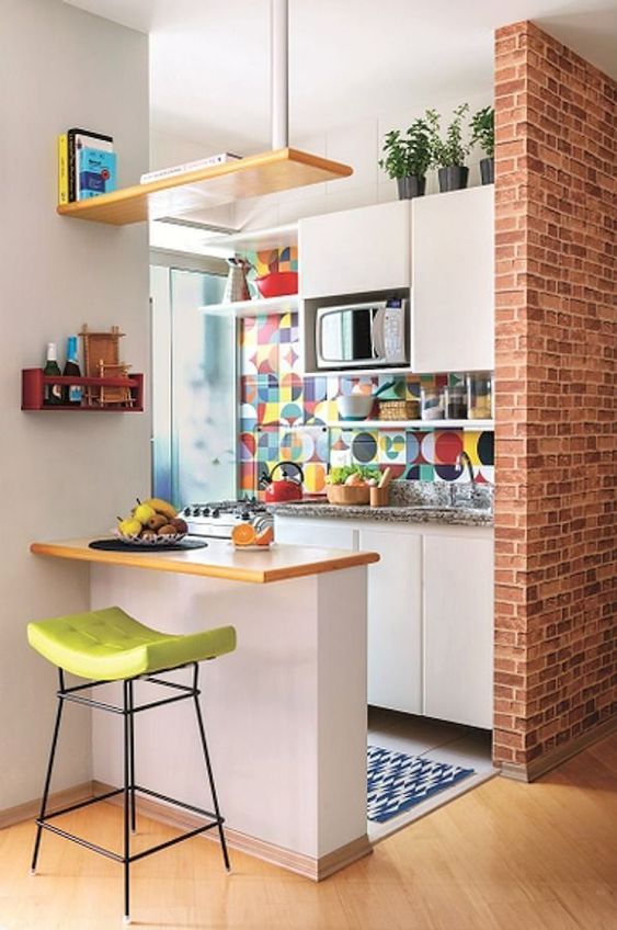 a small eclectic kitchen with white cabinets, grey stone countertops, a small kitchen island, a colorful tile backsplash