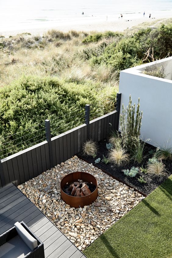 a small terrace with a bit of plants, lawn, a deck and a fire pit space done with large rocks is amazing