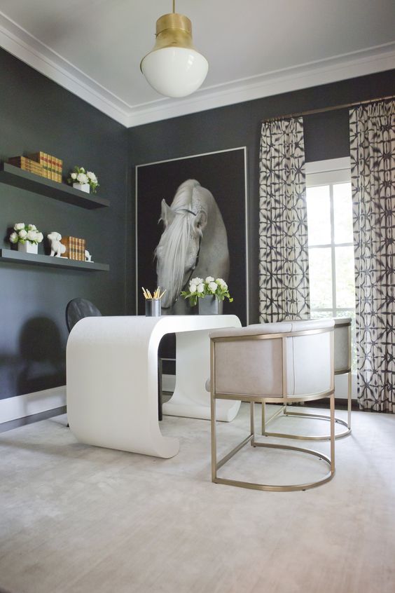 a sophisticated black and white home office with black walls and shelves, a white curved desk and matching creamy chairs, a statement artwork and printed curtains